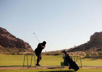 Anonymous man alone practicing golf swing on driving range.