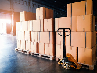 Interior of storage warehouse. Stack of pakaging boxes on pallets and hand pallet truck. Shipment boxes. Supply chain Shipping warehouse logistics and transportation.