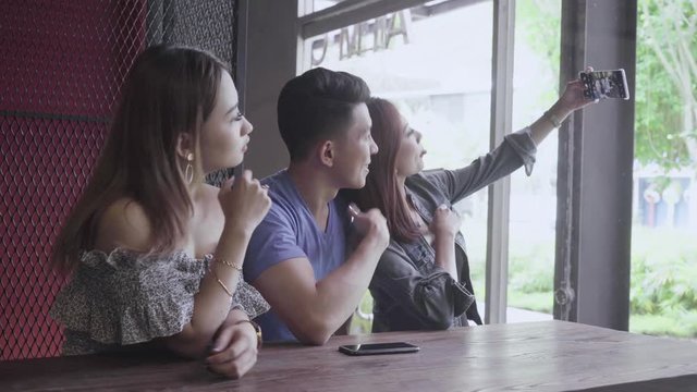 Three young people taking selfie picture in cafe