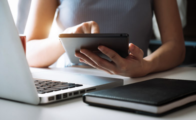 Hands of woman using mobile phone in modern office with laptop and digital tablet at home office