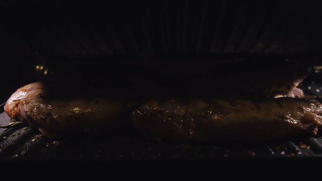 Delicious juicy meat steak cooking on the grill. Cook grilling fresh chicken breast. Fry chicken fillet on electric roaster. Pour salt, rosemary, black pepper. Slow motion.