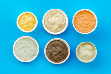 Blue, yellow, white. red, black cosmetic clay background on blue table top-down