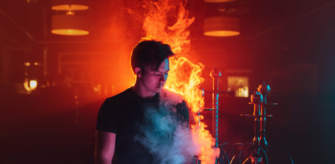 man is relaxing and Smoking a hookah and blowing a cloud of smoke in a lounge cafe