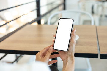 Mockup image blank white screen cell phone.woman hand holding texting using mobile on desk at coffee shop.background empty space for advertise text.people contact marketing business,technology