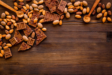 Chocolate frame. Broken slices and nuts on wooden background top-down copy space
