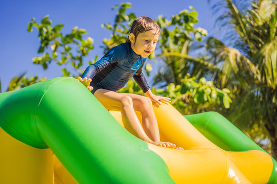 Cute Boy Runs An Inflatable Obstacle Course In The Pool