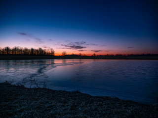 Fototapeta na wymiar Icy Sunrise Over Pond