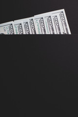 Hundred dollar bills partially visible on a black background, copy paste.
