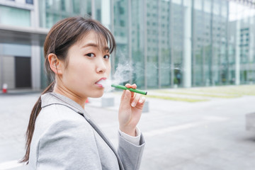 電子タバコを吸う若いビジネスウーマン