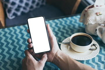 Mockup image blank white screen cell phone.man hand holding texting using mobile on desk at coffee shop.background empty space for advertise text.people contact marketing business,technology