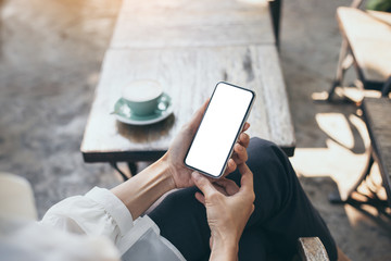 Mockup image blank white screen cell phone.woman hand holding texting using mobile on desk at coffee shop.background empty space for advertise text.people contact marketing business,technology