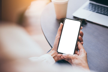 Mockup image blank white screen cell phone.woman hand holding texting using mobile on desk at coffee shop.background empty space for advertise text.people contact marketing business,technology