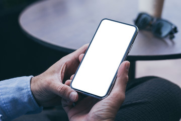Mockup image blank white screen cell phone.man hand holding texting using mobile on desk at coffee shop.background empty space for advertise text.people contact marketing business,technology