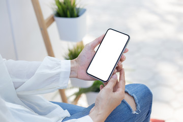 Mockup image blank white screen cell phone.woman hand holding texting using mobile sitting at coffee shop.background empty space for advertise text.people contact marketing business,technology