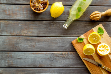 Make lemonade. Drink in bottle near utensil on wooden wooden background top-down copy space