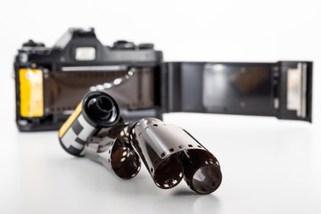 Single lens reflex camera and a film roll on a white background.