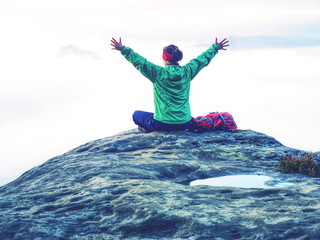Girl on summit hands raised over clouds. Travel Lifestyle
