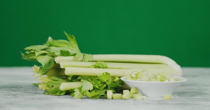 A bunch of celery and sliced celery on the plate slowly rotated.