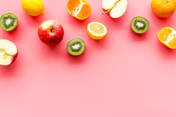 Oranges, lemon, apple, kiwi and grape - healthy food concept with fruits - on pink background top-down frame copy space