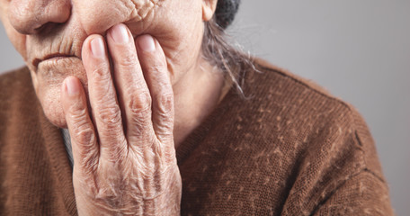 Elderly woman suffering from tooth pain.