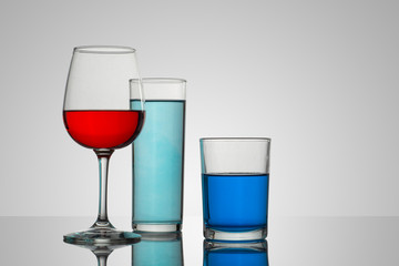 Copa y vasos de cristal con un fondo blanco y bebidas de diferentes tipos y colores, con composiciones atractivas