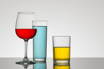 Copa y vasos de cristal con un fondo blanco y bebidas de diferentes tipos y colores, con composiciones atractivas