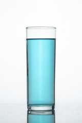 Vaso de cristal con liquido o bebida azul y fondo blanco