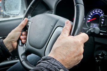 Men's hands on the steering wheel of a car. The driver controls the car.