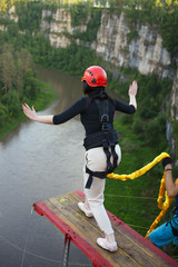 Girl, tied on a safety rope, is preparing to jump from a great height into a deep canyon....