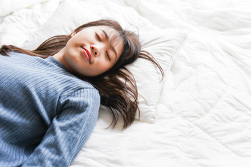 Obraz premium 布団に入って睡眠を取る若い女性