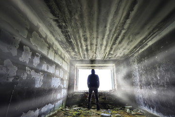 man against the background of a window in a ruined house, horror, fear concept, radiation stalker...