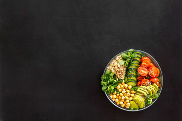 Vegan Buddha bowl. Avocado, quinoa, tomato, spinach and chickpeas vegetables salad on black table top-down copy space