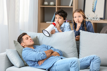 Children playing a prank on their father at home. April Fools' Day celebration