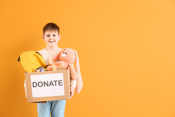 Little boy with donations on color background