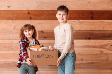 Little children with donations on wooden background