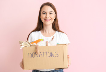 Volunteer with donations for orphans on color background