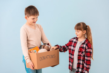Little children with donations on color background