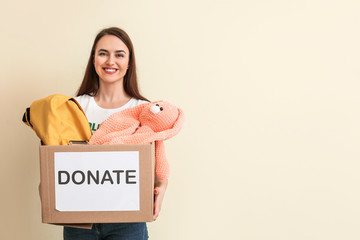 Volunteer with donations for orphans on color background