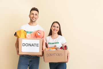 Volunteers with donations for orphans on color background