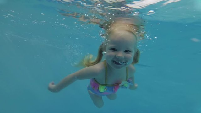 A child dives underwater in the pool. Little girl in the swimming pool