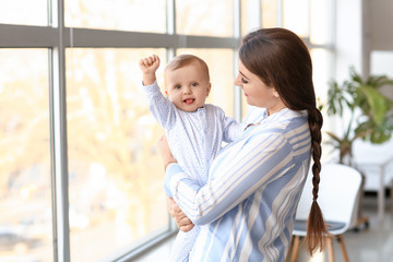 Happy mother with cute little baby near window