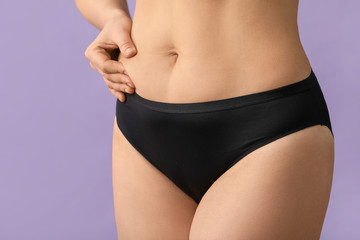 Young woman with cellulite problem on color background, closeup