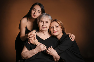 Portrait of mature woman with her adult daughter and mother on dark color background