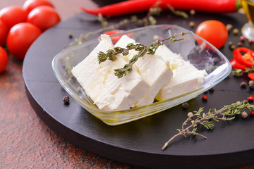 Tasty feta cheese with vegetables and spices on board