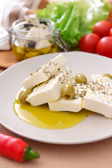Plate with tasty feta cheese, oil, olives and spices on table