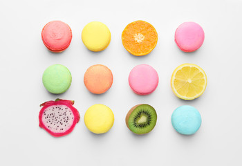 Tasty macarons with fruits on white background