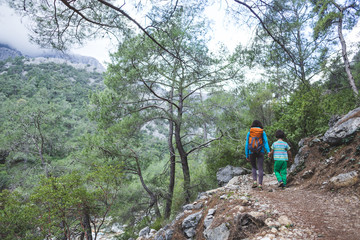 A woman walks with her son through the forest.
