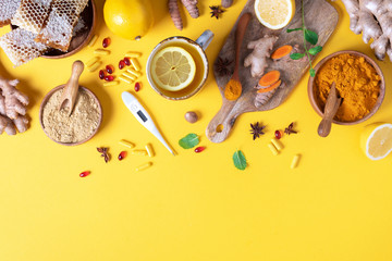 Medical care concept. Cold, flu treatment. Ginger, lemon, honey, pills, drugs, supplements, thermometer on yellow background. Natural alternative holistic approach. Top view, copy space