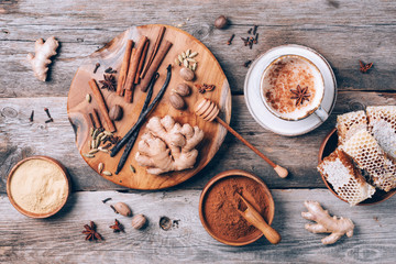 Indian masala tea with spices. Tea with milk, cloves, ginger, cardamom, cinnamon, anise, vanile, honey, nutmeg on wooden background. Top view, copy space. Antiviral beverage. Healthy ayurvedic drink