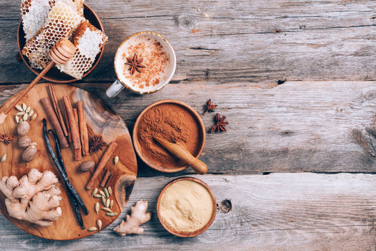 Indian masala tea with spices. Tea with milk, cloves, ginger, cardamom, cinnamon, anise, vanile, honey, nutmeg on wooden background. Top view, copy space. Antiviral beverage. Healthy ayurvedic drink